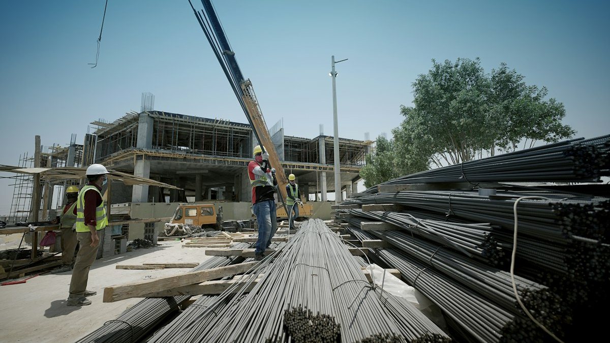 Real construction site with tower crane and workers handling rebar lifting with slings — OM Enterprise